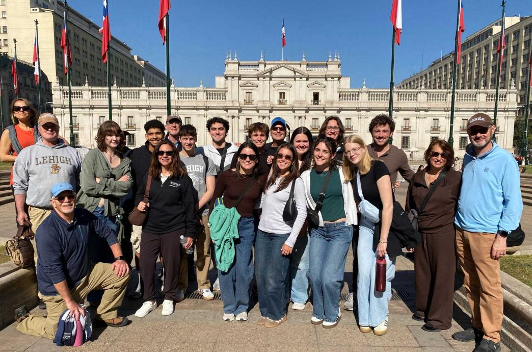 A group of students stand in front of Plaza de la Constitución in front of the presidential palace, Palacio de La Moneda.
