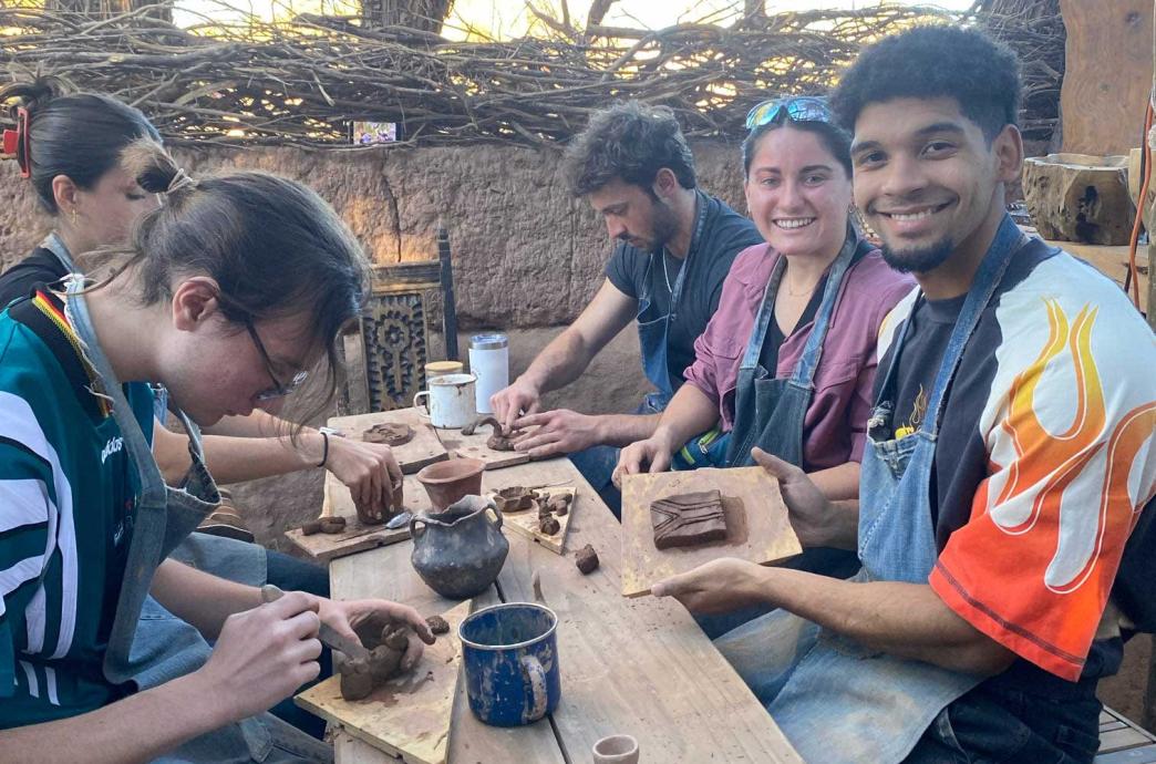 A group of students make clay sculptures. Michael holds up his work in progress and smiles.