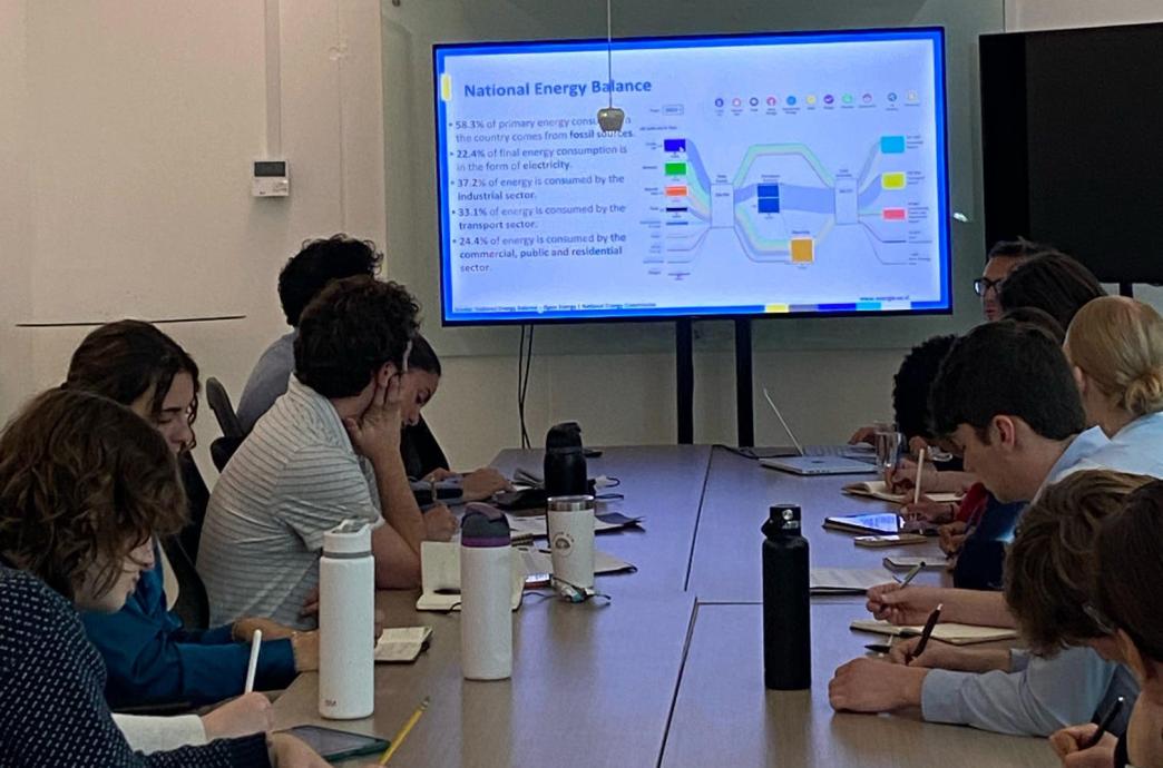 A group of students sit around a conference table and look at a slide that reads 'National Energy Balance.'