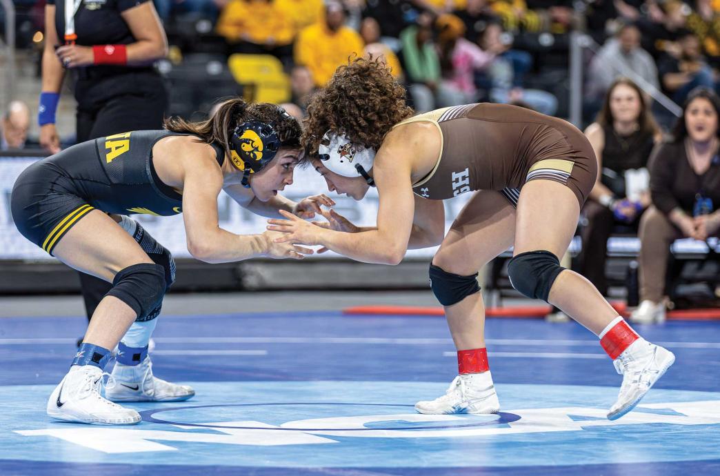 Two women in wrestling gear crouch down and prepare to lock hands.