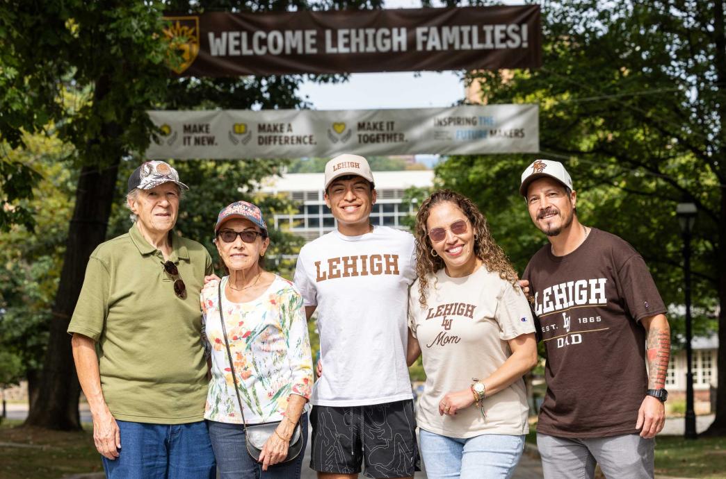 A family stands together with their arms around each other while wearing Lehigh merch; the student stands in the middle. 