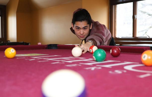 JC Santamaria ’23 leaning over a pool table lining up his shot
