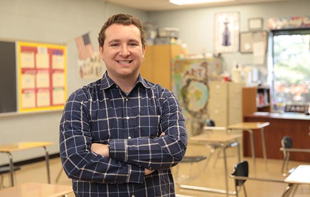 Joshua Reznik stands in a classroom