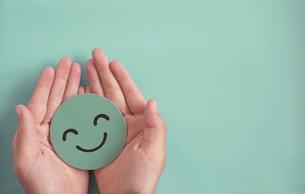 Green smiley face cupped in a pair of hands