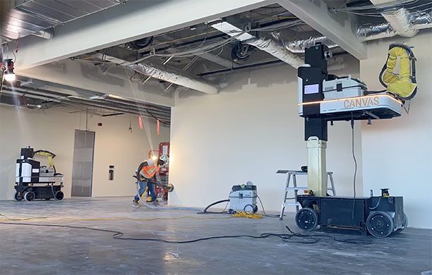 Worker sands a wall with arm of construction robot