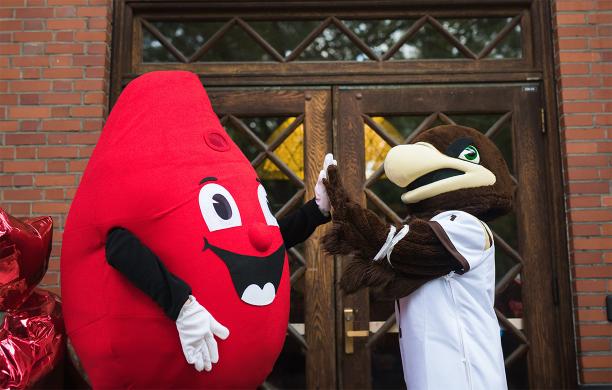 Blood Mascot and Lehigh University Mascot Clutch high-five in front of a building