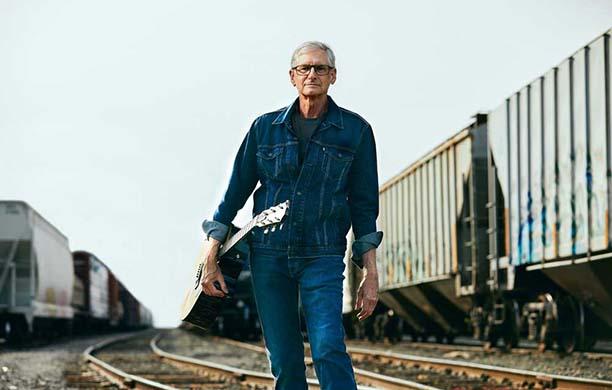 Jim Standard with his guitar in a train yard