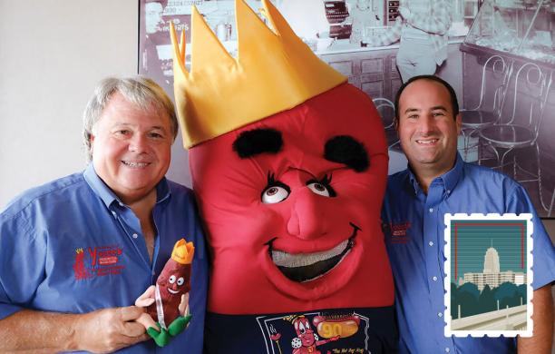Gary Iacocca and the Yocco's mascot standing before vintage photography smiling