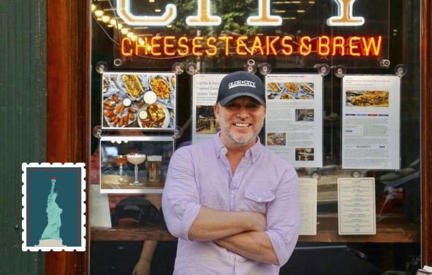 Evan Stein ’93 leaning against a large display window that reads Olde City Cheesesteaks and Brew