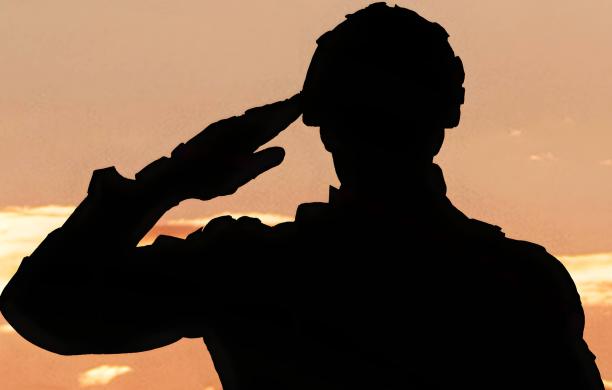 A soldier saluting at sunset