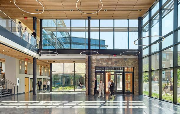 People enter the interior lobby of the Business Innovation Building, complete with high ceilings and floor-to-ceiling windows.