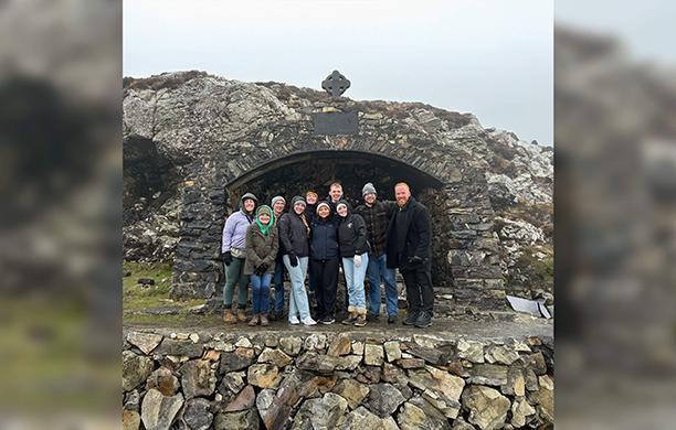 A group of young people and a priest in front of a cave where St. Patrick once prayed. 