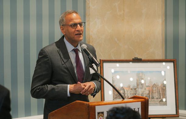 Richard Verma stands at a Lehigh branded podium, speaking into a long stationary microphone with artwork behind him signifying his award.