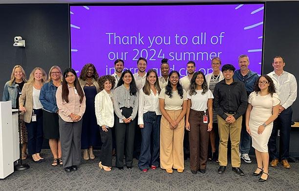 A group of students stand in front a screen that conveys a thank you message.