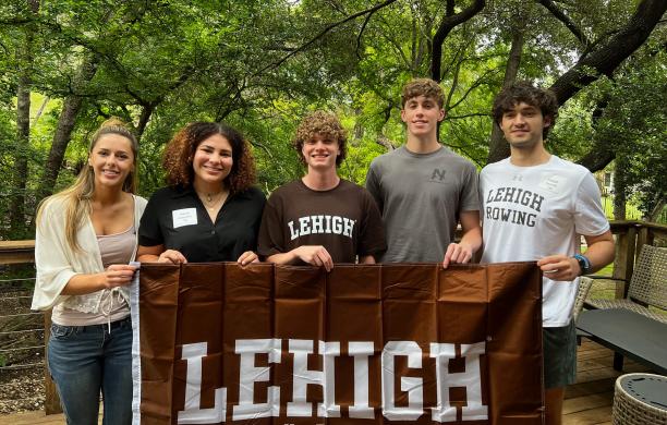 Students standing together holding a brown Lehigh flag.