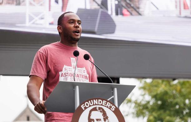 Jermaine Marshall Standing behind a podium and speaking during Family and Founder's Weekend