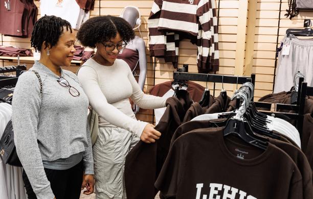 Two women admiring a brown Lehigh hoodie while standing together in the Lehigh Store
