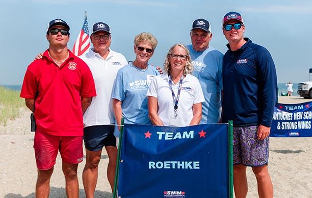 The Roethke family stand on the beach in front of their team sign