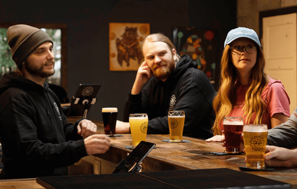 Lemery stands behind the bar and serves four patrons different beers.