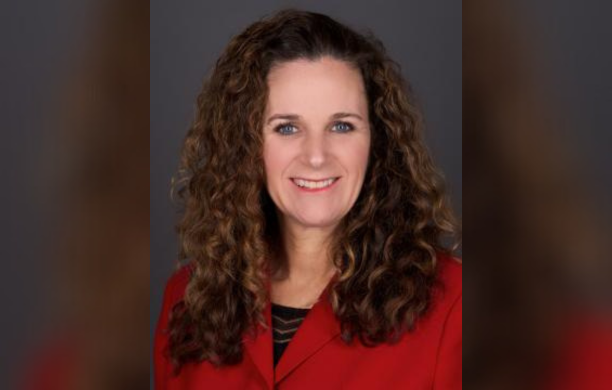 Jennifer Nelson smiling for a photo while wearing a red blazer