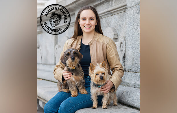Aliza Bodzin sitting outside on a stone bench with her two dogs on her lap