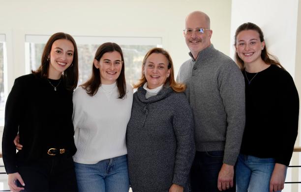 Faith Glazier and Rob Weisstuch stand for a photo flanked by their three daughters, all wearing sweaters