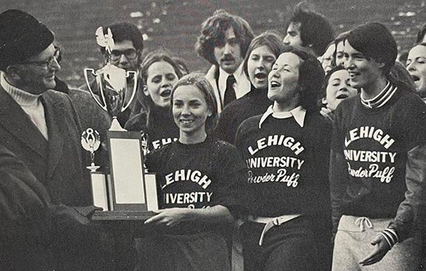A man hands a trophy to the women of the Lehigh Powderpuff Football team