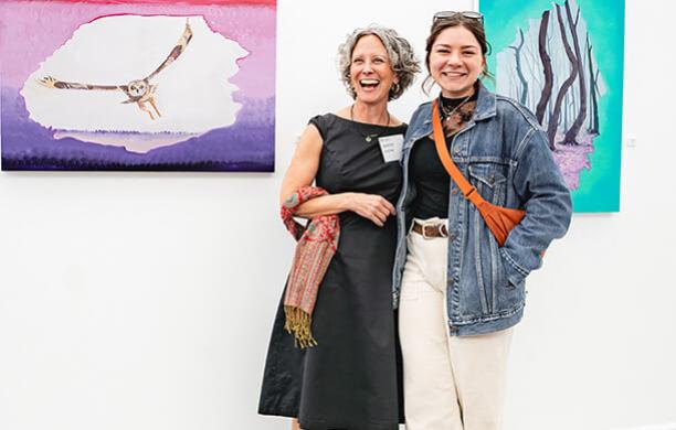Deirdre Murphy and Holly Fasching '26 smile in front of paintings of birds.