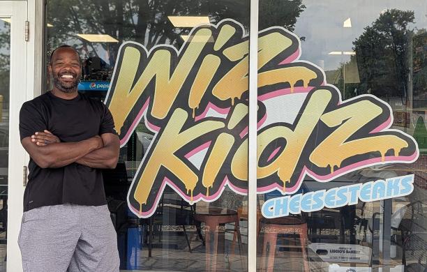 Mo Taylor standing in front of his Bethlehem restaurant Wiz Kidz, which features colorful, retro-inspired decor.