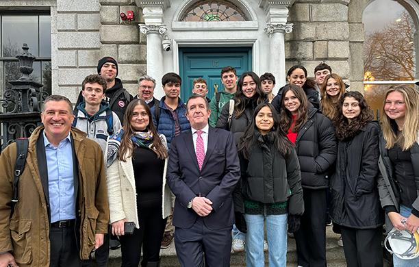 Wilson and a group of students bundled in thick coats stand alongside a business professional in front of a property in Dublin.