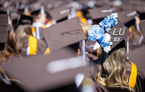 A decorated cap in a sea of brown caps at Commencement.