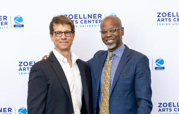 Marc Falato smiles with Mark Wilson in front of a “Zoellner Arts Center” step and repeat, Wilson’s hand on Falato’s shoulder.