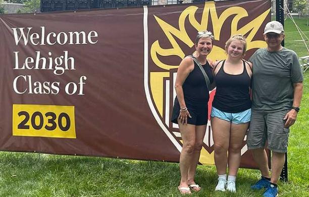 Gillian, Glenn, and Trudy stand in front of a banner that reads 'Welcome Lehigh Class of 2020' and smile.