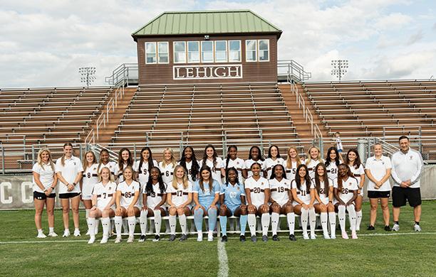 Women's soccer team and coaches pose at the stadium for a team photo