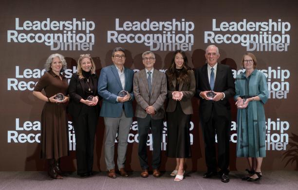 The six recipients stand together alongside President Helble in the center. They all wear business attire and hold their awards.