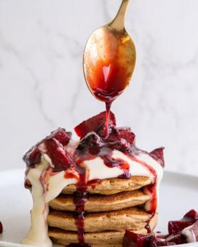 Stack of pancakes drizzles with a fruit sauce and ice cream