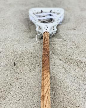 wooden lacrosse stick laying in the sand