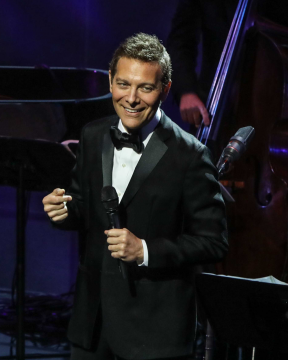 Michael Feinstein wearing a black suit performing on stage