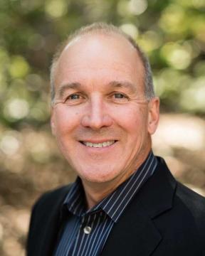 Mark Stutzman wearing a suit jacket and smiling.