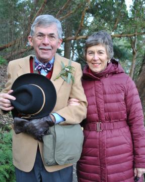 John and Pam Sebastian wearing winter clothing backed by green trees.