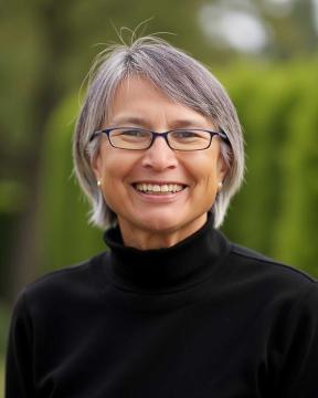 Sandy Denton wearing a black turtleneck and smiling