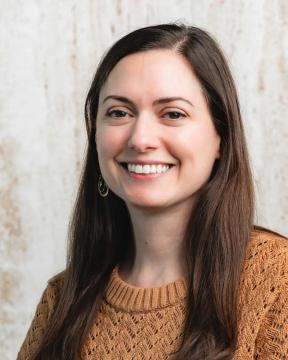 A woman smiling in front of a plain background.