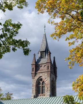 stone building with fall leaves bordering the cloudy sky