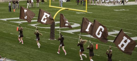 Lehigh cheerleaders carry flags that spell Lehigh