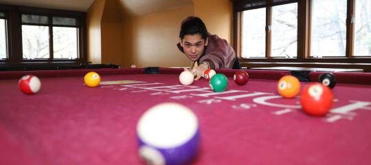 JC Santamaria ’23 leaning over a pool table lining up his shot