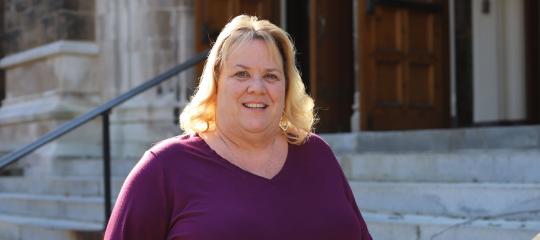 Mary Fronheiser standing on the steps of Alumni Memorial