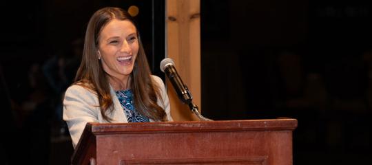 Morgan Nelson speaking behind a wooden podium