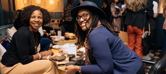 Two African American women chatting and enjoying hors d'oeuvres