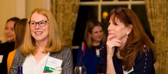 Two women sitting together and listening to a speaker