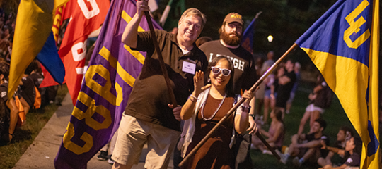 Lehigh University alumni walk through campus during The Rally waving their class flags.